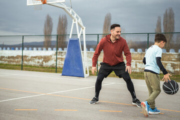 Fototapeta premium Father and son playing basketball on outdoor court