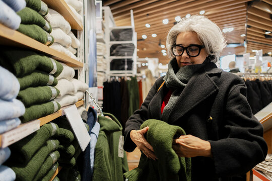 Customer choosing sweater in retail clothing store