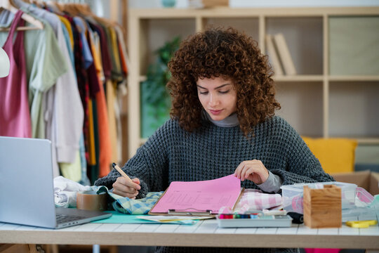 Designer planning garment patterns at sewing workspace