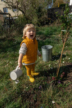 Child watering plant in spring outdoor garden learning about nature