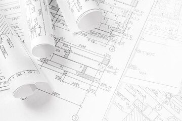 Architect workspace with blueprints, laptop and sketches on bright desk, modern design studio for CAD and planning, minimal clean office background with copy space and daylight.