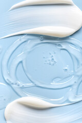 Close-up of cosmetic cream smears, smooth and shiny texture, blue background