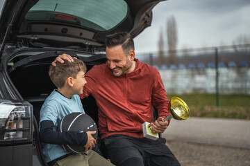 Father and son celebrating basketball success with trophy