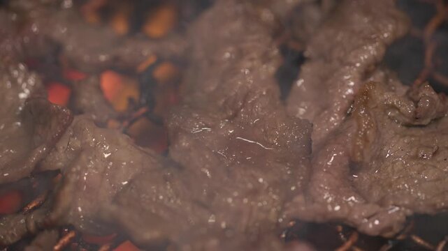 Slow motion close-up of Griling Korean traditional BBQ bulgogi on the grill