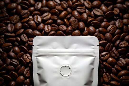 Top View of Matte White Foil Bag with Valve Placed on Dark Roasted Arabica Coffee Beans