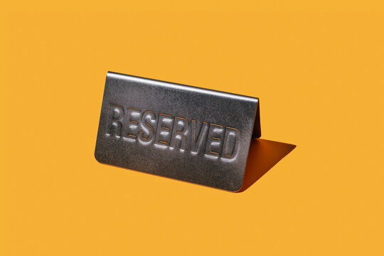 Reserved metal sign on orange background symbolizing exclusivity