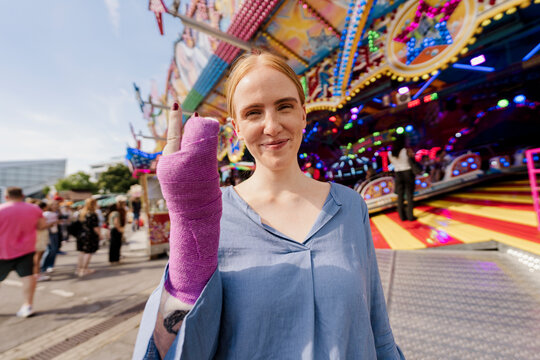 Smiling young woman with plaster cast at colourful summer fair
