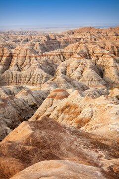 Panoramic view of striped buttes and eroded hills at a scenic overlook in Badlands National Park, South Dakota, under a clear blue sky.