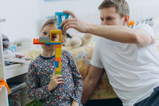 Father and daughter playing with building blocks at home