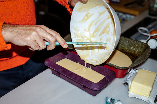 Pouring cake batter into mold for homemade baking in kitchen