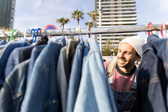 Smiling customer shopping for denim at flea market in Barcelona