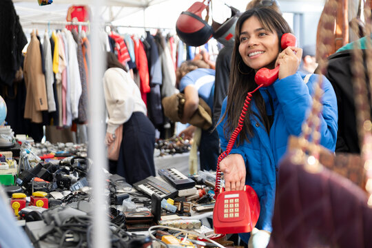 Smiling customer holding vintage red telephone at Barcelona flea market