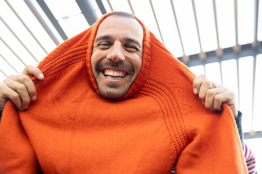 Customer laughing and trying on orange sweater at flea market