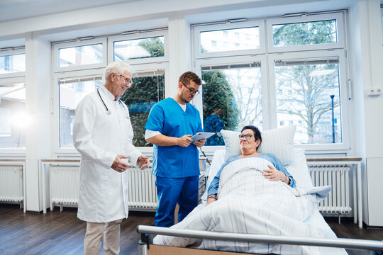 Doctor and nurse consulting with patient in hospital room
