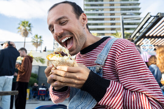 Laughing person enjoying street food outdoors at the flea market