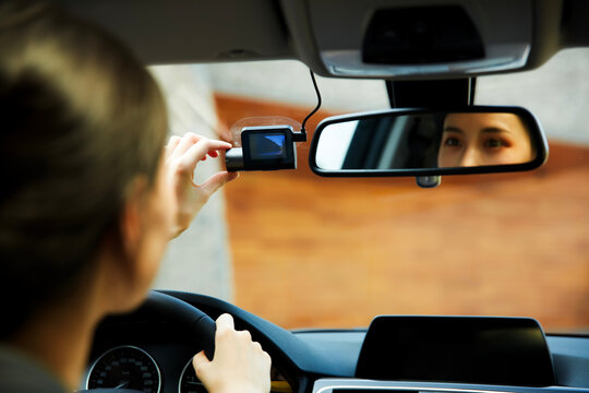 An Asian girl adjusts the dashcam inside the car.
