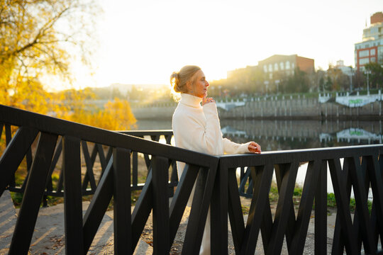 Woman walking along embankment in golden autumn morning light