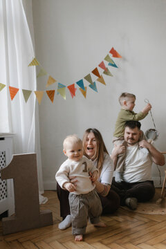 Family celebrating baby birthday together in decorated living room