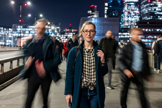 Woman waiting on busy London bridge at night