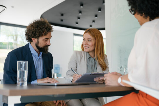 Business partners signing contract and discussing new project in office
