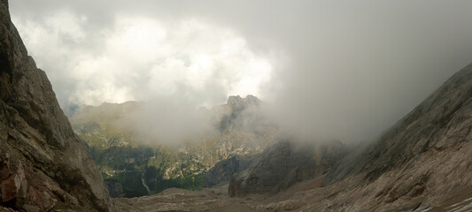 Cloud filled mountain valley framed by limestone walls in Dolomites mountains Italy