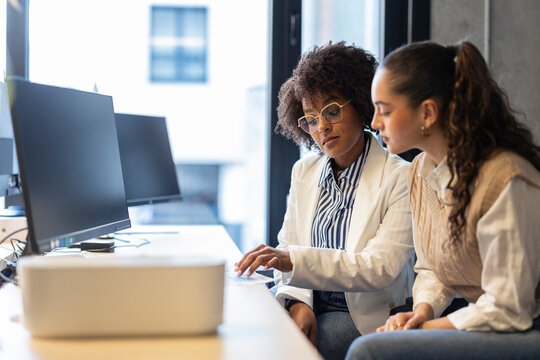 Businesswoman mentoring colleague during office discussion at workspace