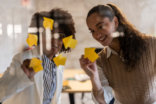 Two professionals brainstorming with sticky notes in a modern office