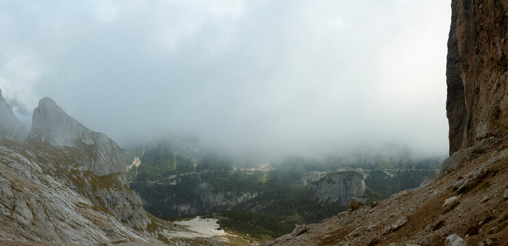 Foggy alpine valley view framed by limestone cliffs in Dolomites mountain landscape Italy