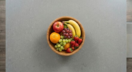 Fresh fruit bowl on a kitchen counter with apples, bananas, grapes, oranges, and strawberries