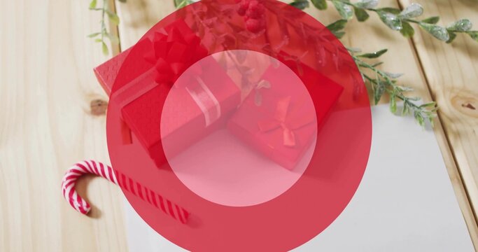 Displaying red gift boxes with ribbons on light wooden tabletop, featuring candy cane, white card