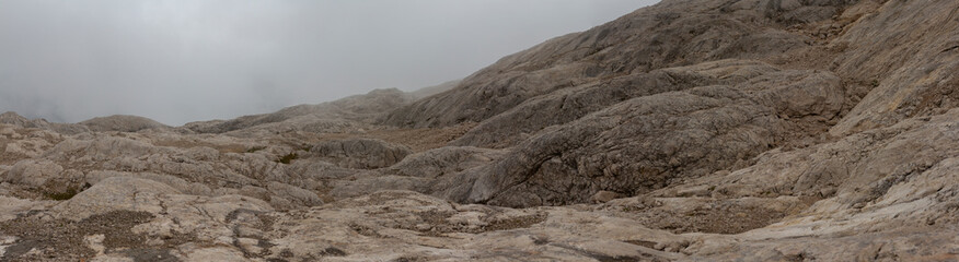 Barren rocky alpine slope disappearing into fog high altitude Dolomites mountain landscape Italy