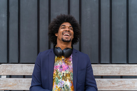 Laughing stylish man sitting on a bench