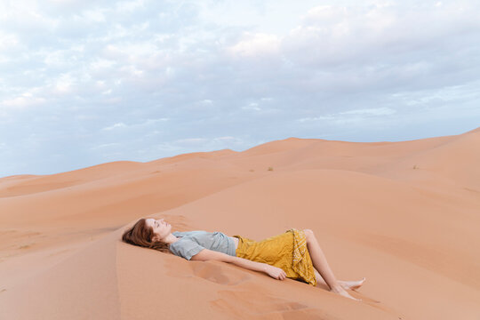Young woman lying in sand dune in Sahara Desert, Merzouga, Morocco