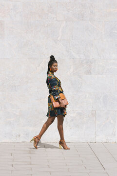 Portrait of chic woman wearing patterned dress walking outdoors