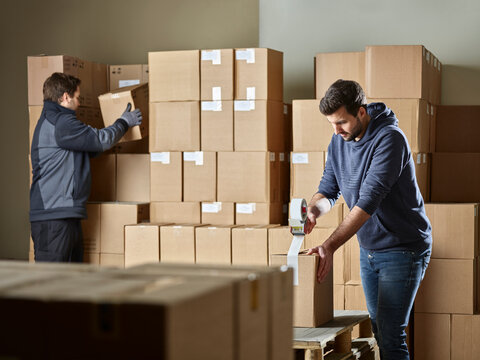 Workers closing packages with package tape
