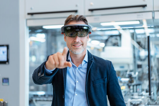 Smiling businessman wearing AR glasses in a modern factory