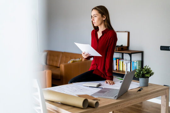 Woman in office holding paper with wind turbine model on table