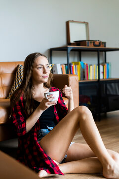 Relaxed young woman eating cereals in living room at home