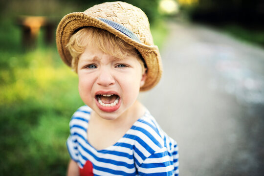 Portrait of screaming toddler wearing straw hat