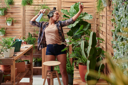 Happy young woman dancing on her terrace while gardening