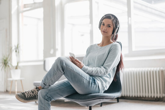 Young woman making a video call from her mobile phone, wearing headphones