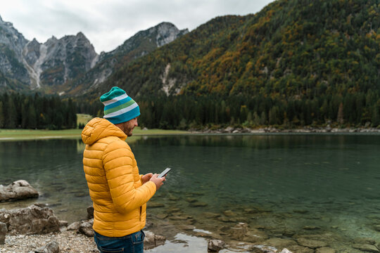 Hiker using smartphone at Laghi di Fusine, Friuli Venezia Giulia, Italy