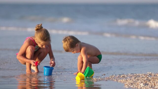 Older sister playing with younger brother aground near the shore on summer vacation