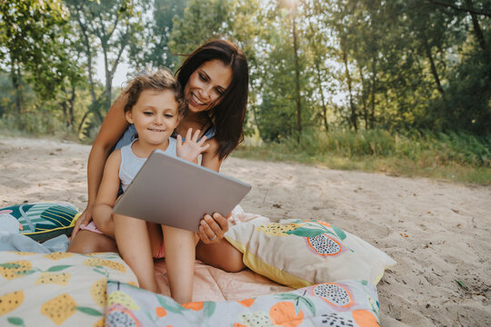 Mother and daughter making a video call at beach on sunny day