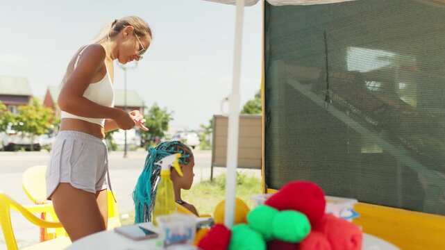 Many threads and ribbons lie on the table against the background of a girl whose African braids are weaving