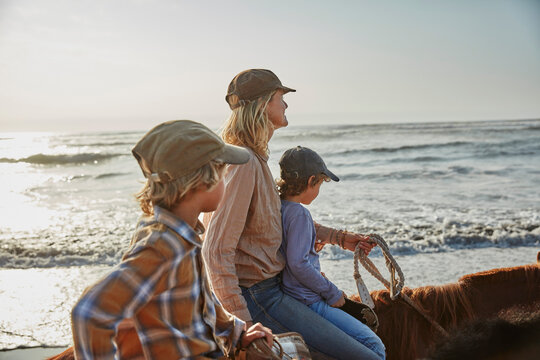 Chile, Vina del Mar, mother with two sons riding horses on the beach
