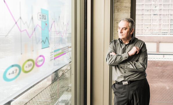 Businessman looking at windowpane with data in office