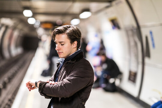 UK, London, businessman waiting at underground station checking the time
