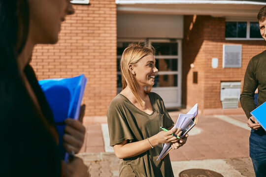 Smiling students standing outdoors with documents
