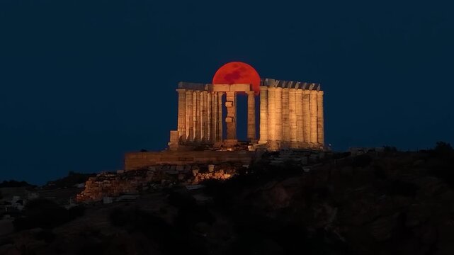 Full, red moon, or Blood moon, rise behind the ancient Tempel of Poseidon in Sounion, Attica, Greece